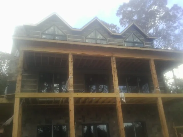 Dormers and porch framing on a large log home under construction — Roof Coating work by our crew in Capron