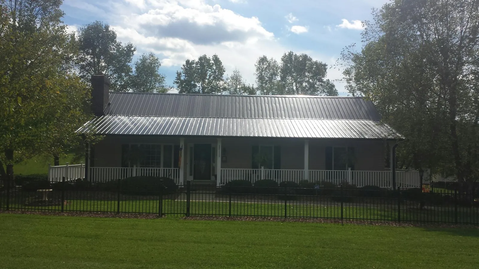 Gray metal roof on a brick ranch with a full width front porch — Gutter Guard Installation work by our crew in Capron