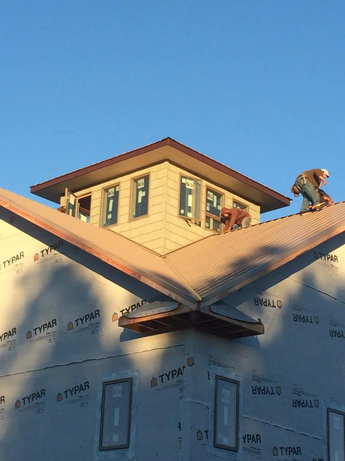 Roofers working around a rooftop cupola on a new metal roof at sunset — Roof Waterproofing in Capron by Roofing Brothers